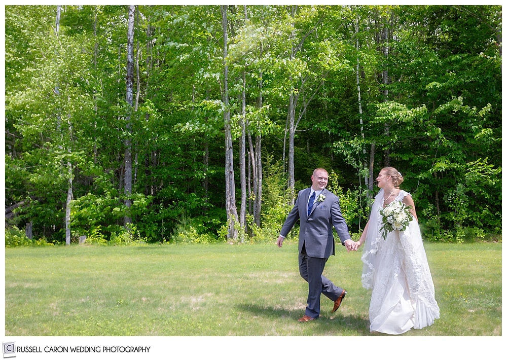 bride and groom holding hands, walking in a field