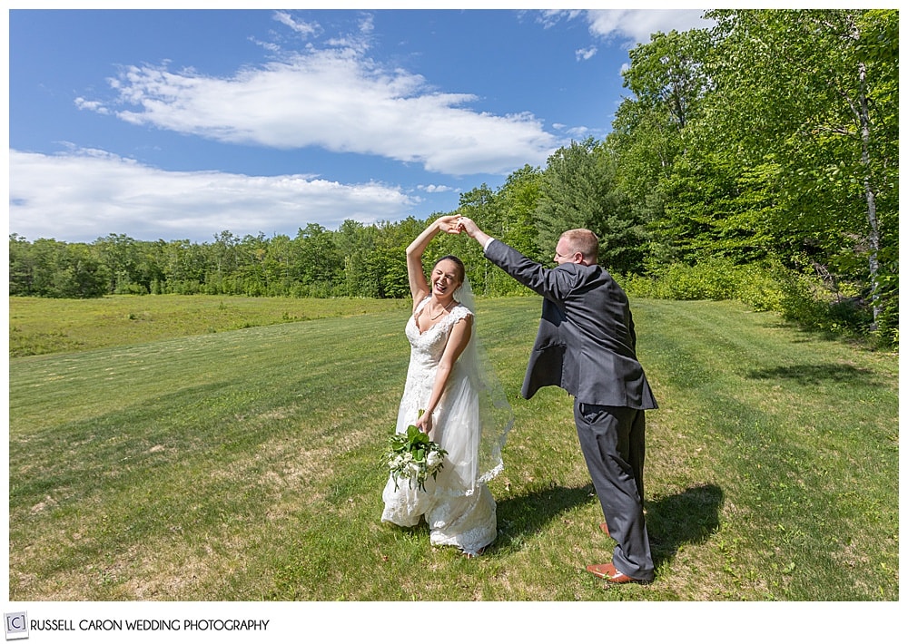 bride and groom twirling and laughing in a field