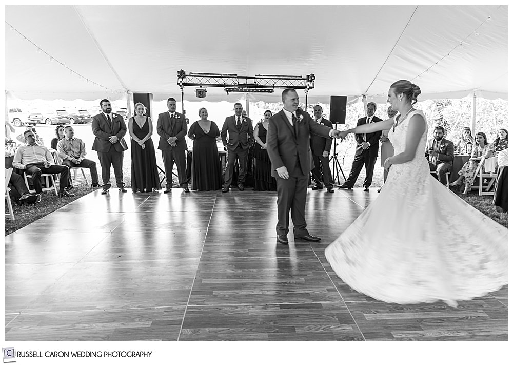 black and white photo of groom twirling bride on the dance floor