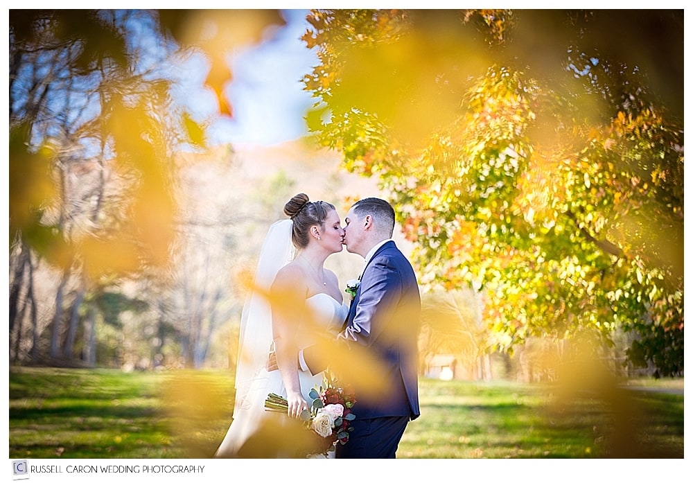 bride and groom kissing in the Maine fall foliage