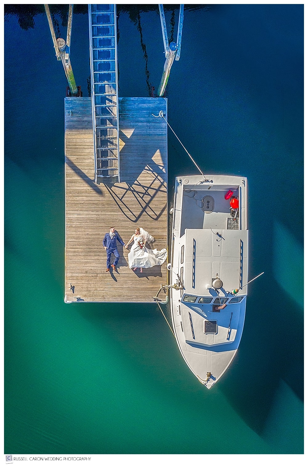 Maine drone wedding photographers photograph a bride and groom on a dock in Camden, Maine