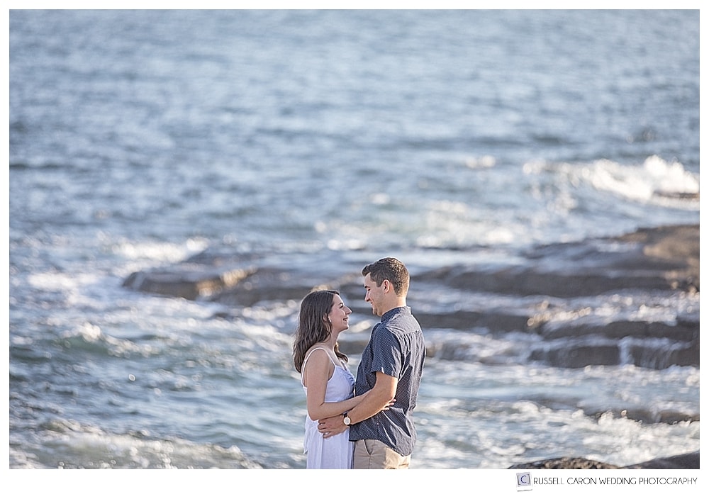 man and woman facing each other at their Nubble Light engagement photo session