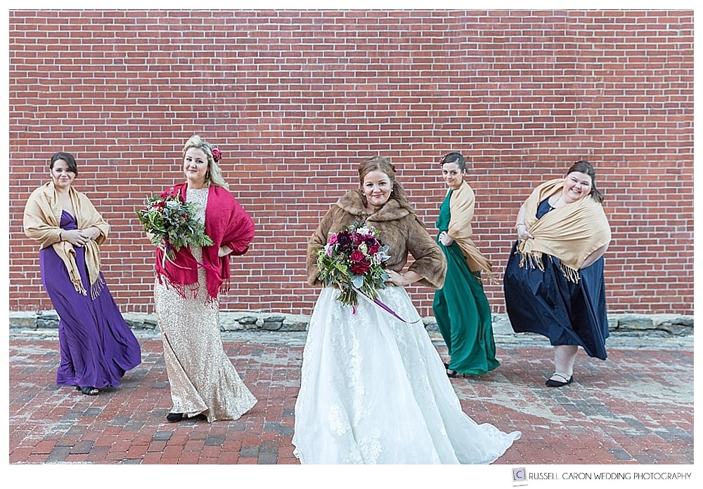 bride and bridesmaids in front of brick wall