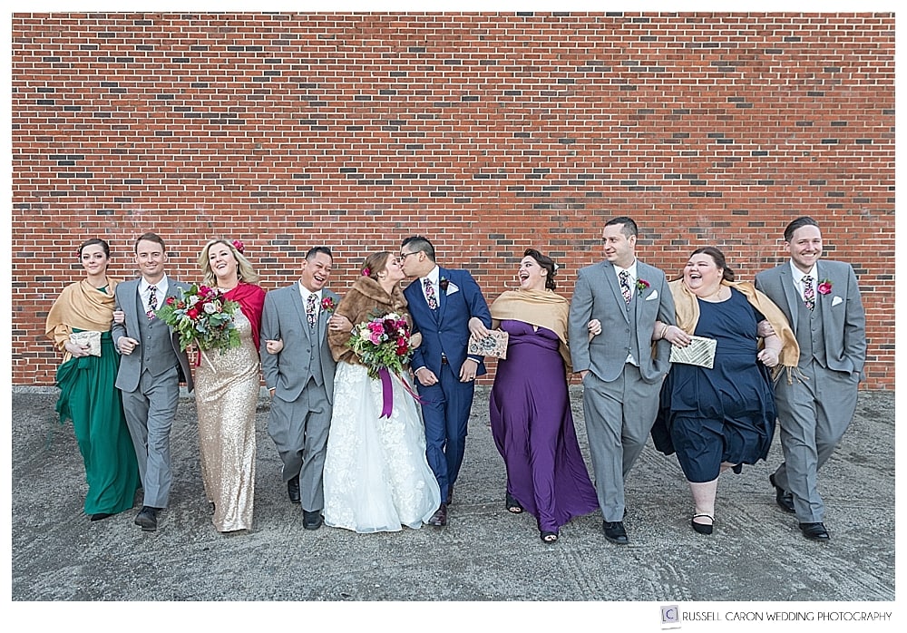 bride and groom with wedding party walking arm in arm