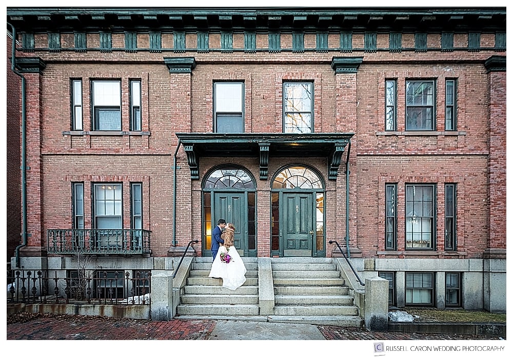 bride and groom standing on the steps of a brick building
