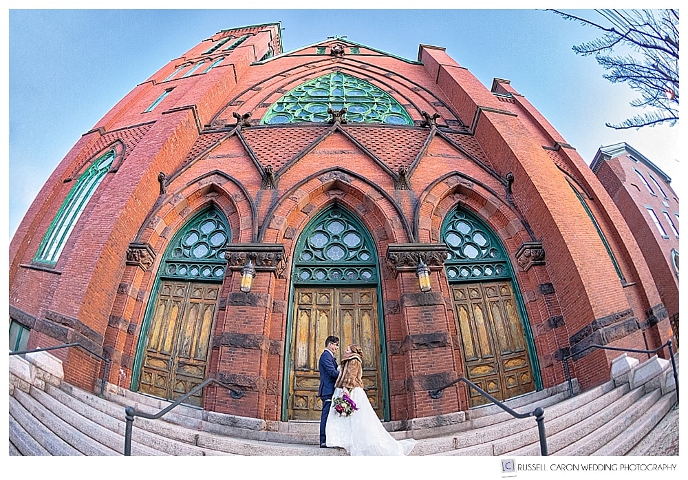 bride and groom standing on the front steps of a cathedral in Portland Maine
