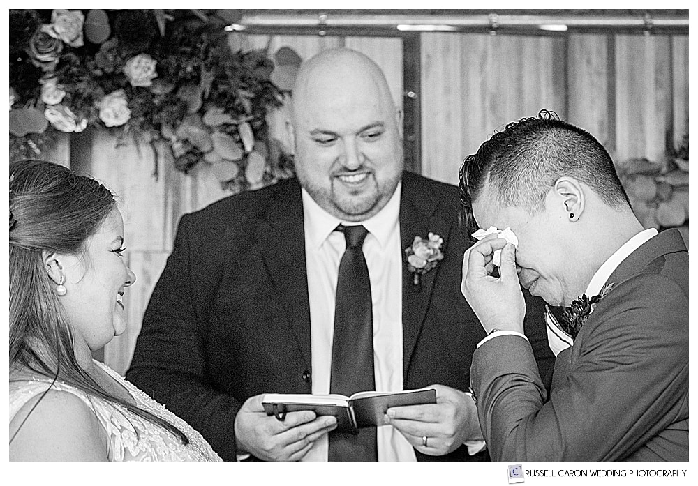 Sweet wedding moment black and white photo of a bride and groom wiping his eyes 