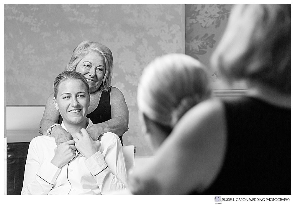 Black and white photo of two women hugging in a mirror during a touching Colony Hotel wedding image