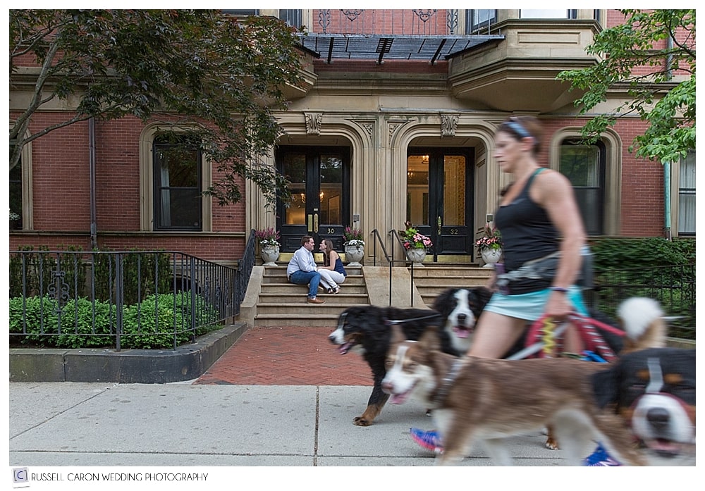 couple-sitting-on-steps-in-boston-while-dog-walker-walks-by