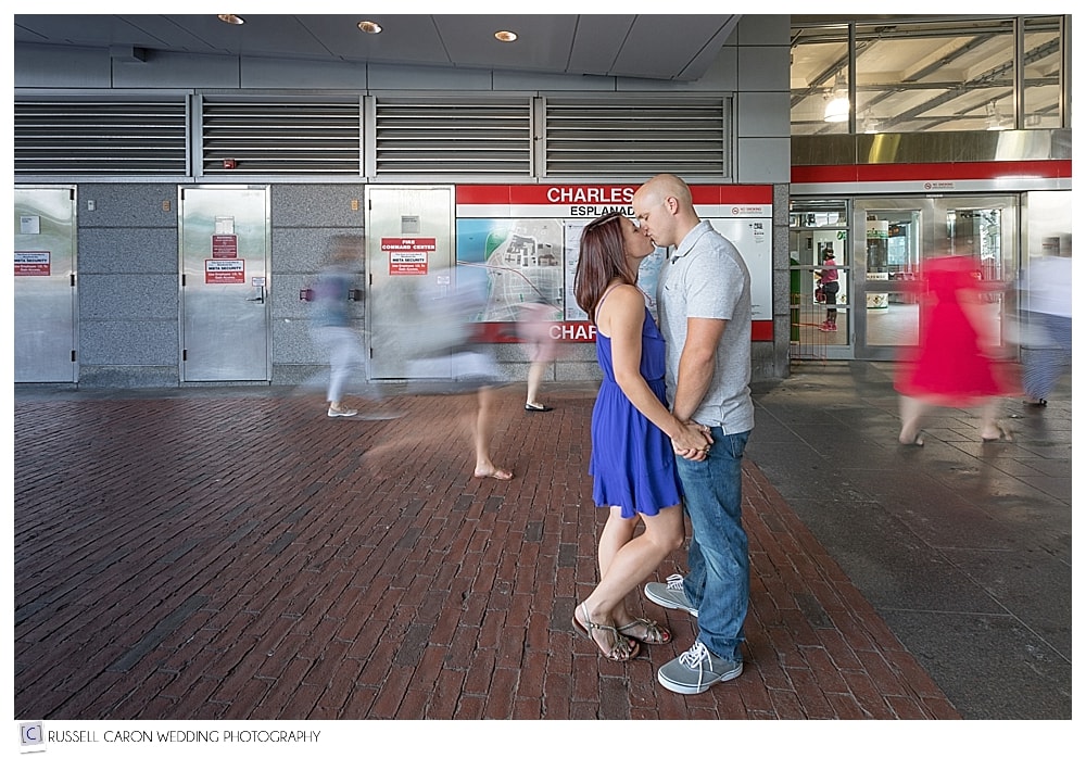 man and woman kissing each other, in front of subway station map in Boston