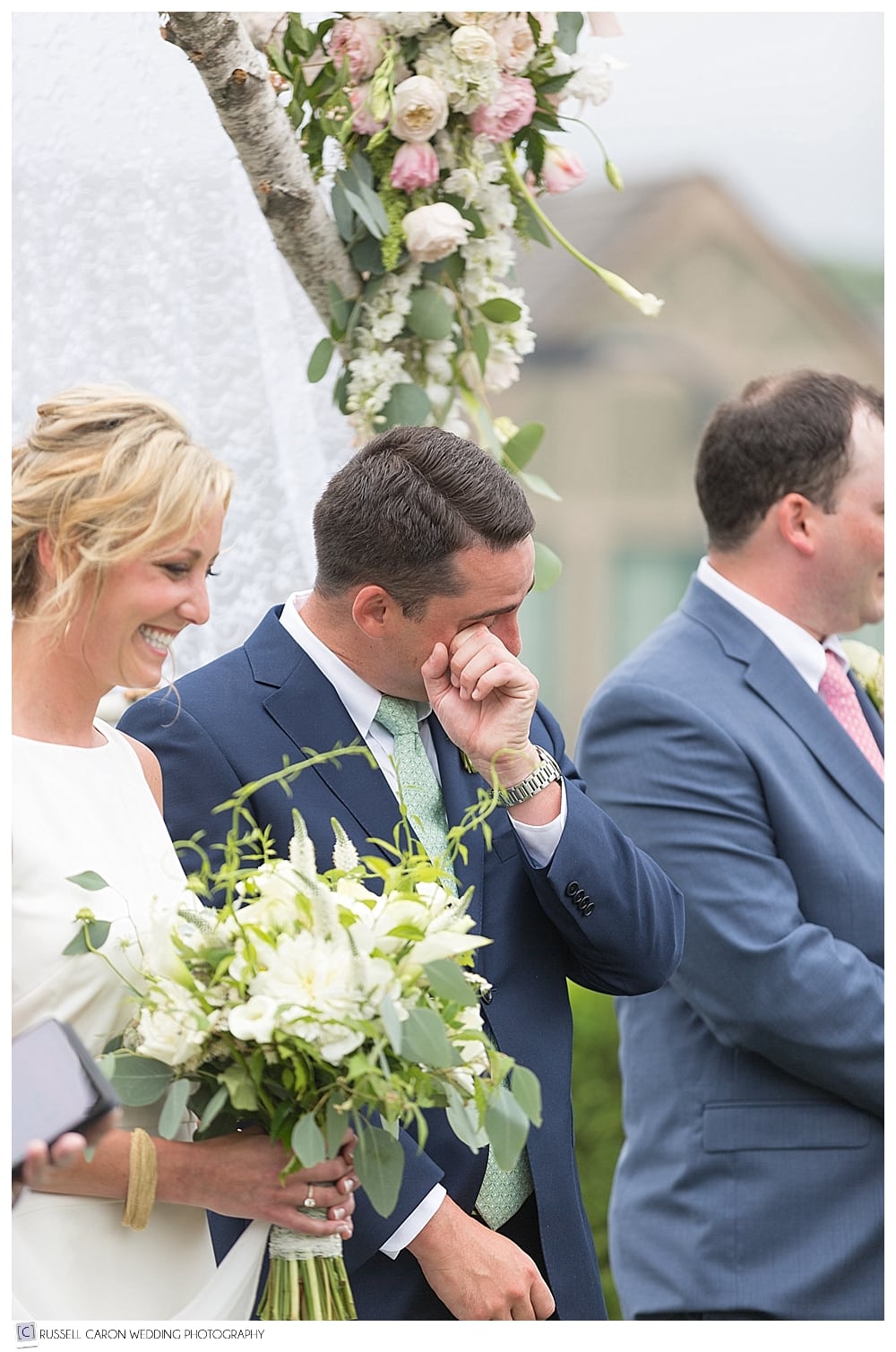 Groom wipes a tear from his eye