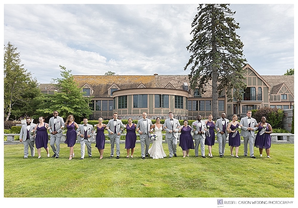 bridal party walking arm in arm on the lawn of the Bar Harbor Club. 