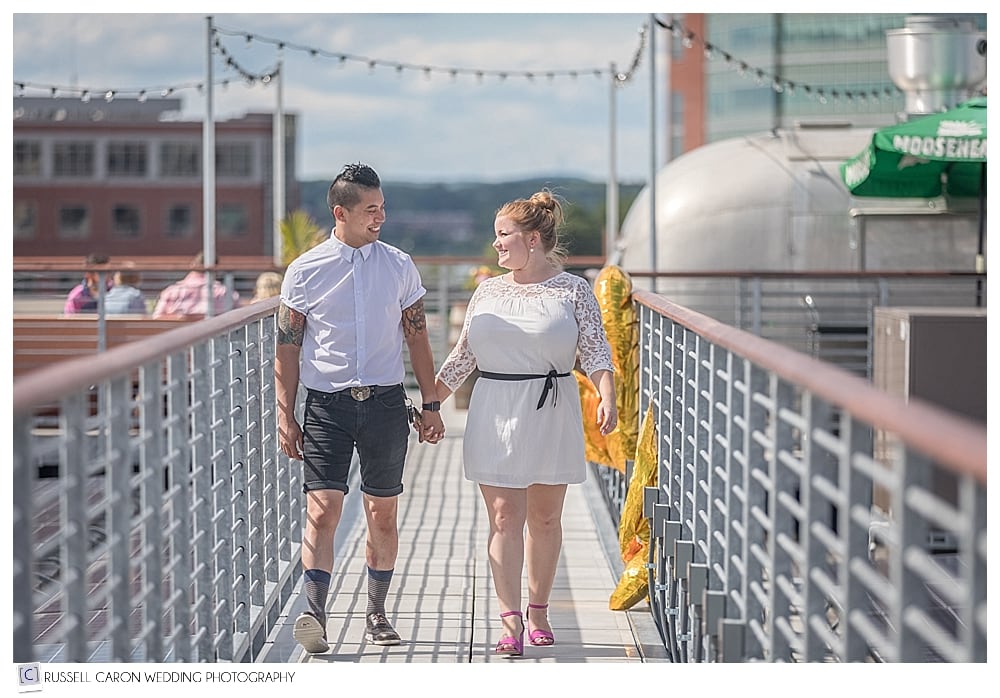 engaged couple walking hand in hand on the rooftop deck at Bayside Bowl, Portland Maine