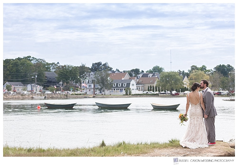 bride and groom standing on the bank of the Kennebunk River with 3 dories behind