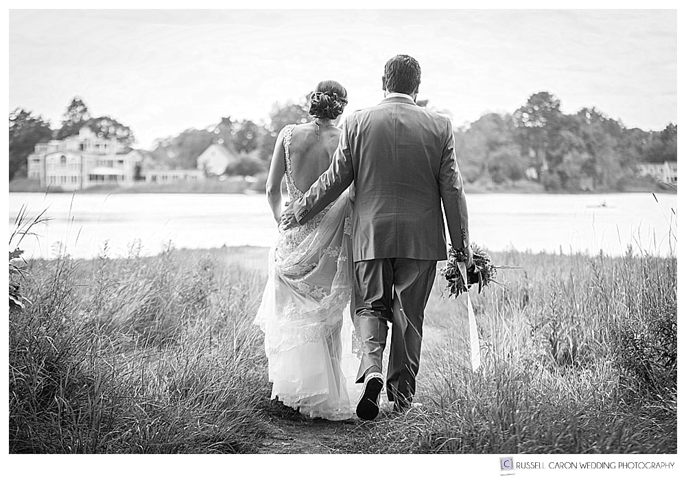 black and white photo of bride and groom walking away