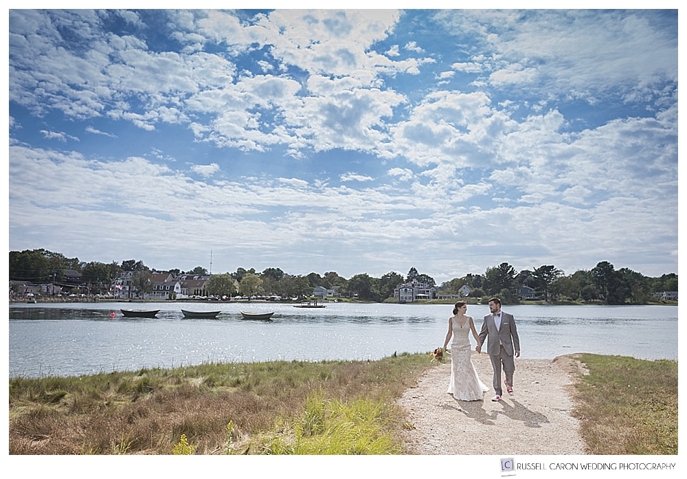 bride and groom holding hands and walking along a dirt path on the Kennebunk River, Kennebunkport, Maine