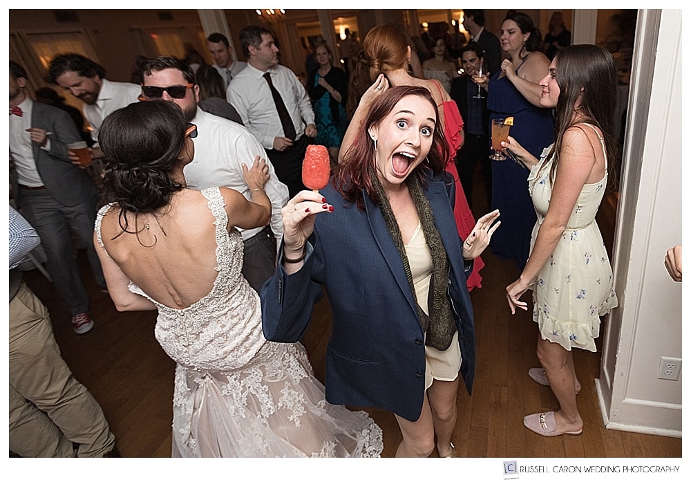 guest dancing during wedding reception, holding a red popsicle