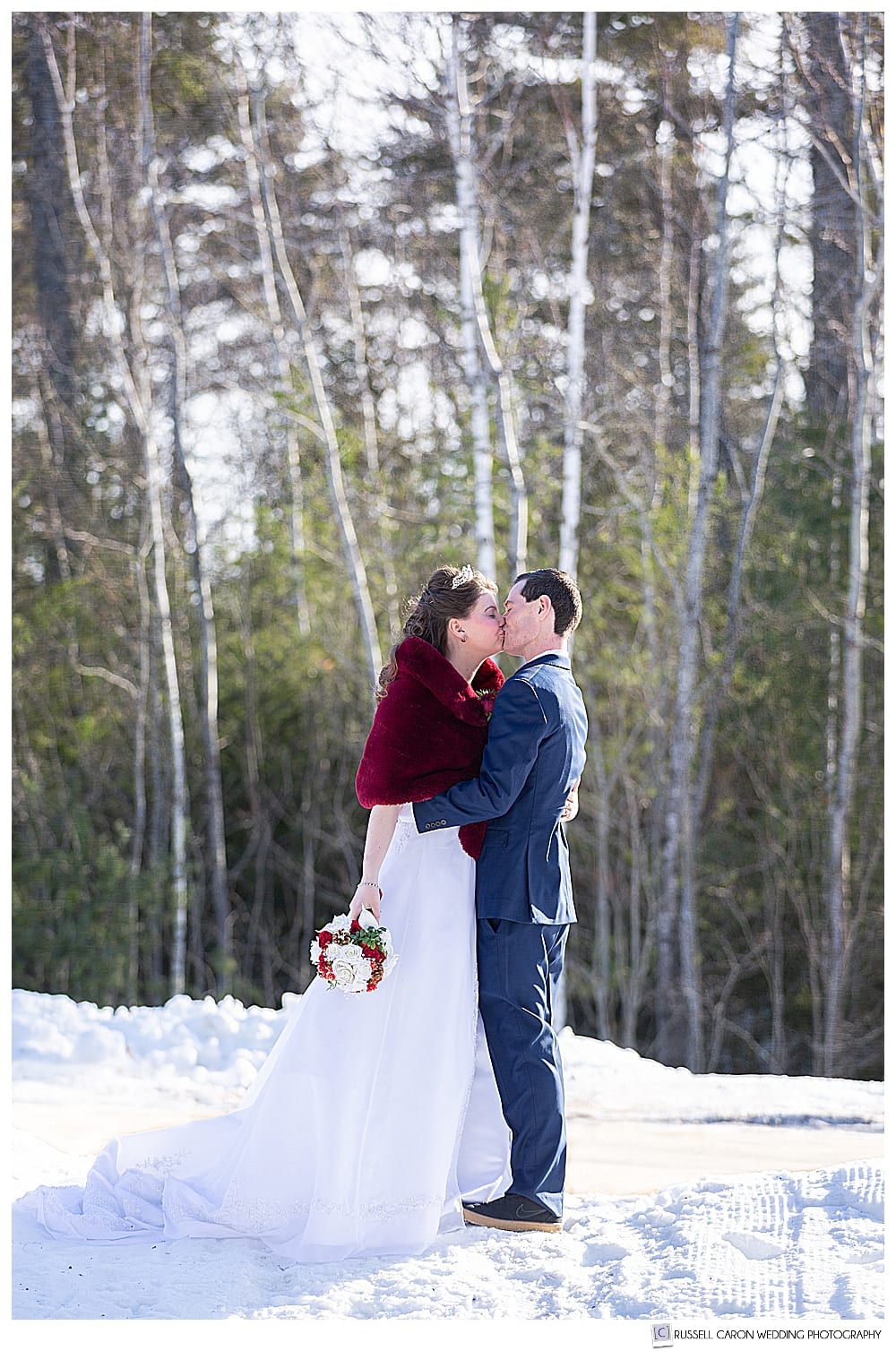 bride and groom kissing in the snowy woods 