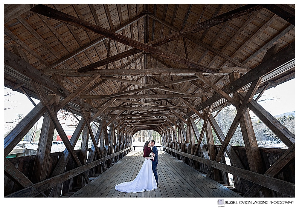 bride and groom kissing in the Newry Maine covered bridge
