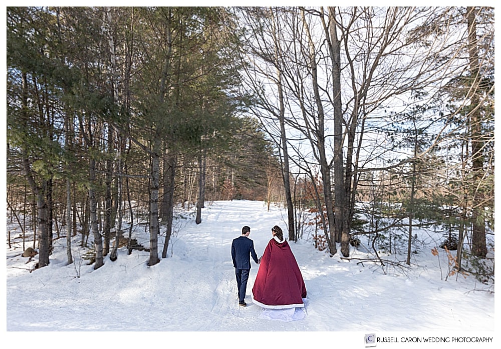 bride and groom walking in the snow during their Bethel Maine wedding
