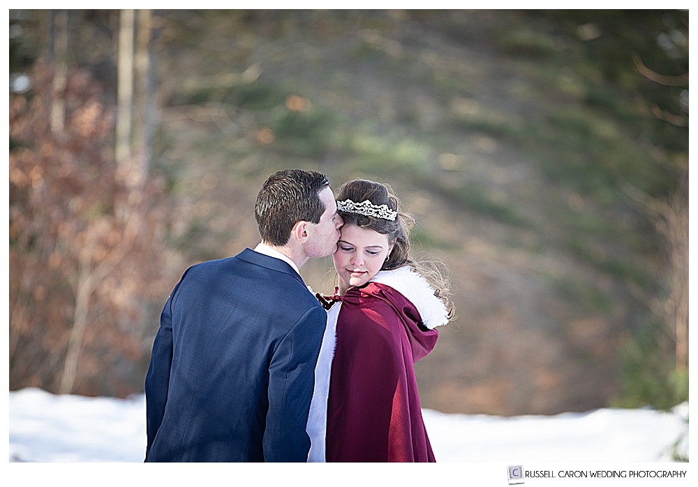 groom kissing bride, wearing a red cape 