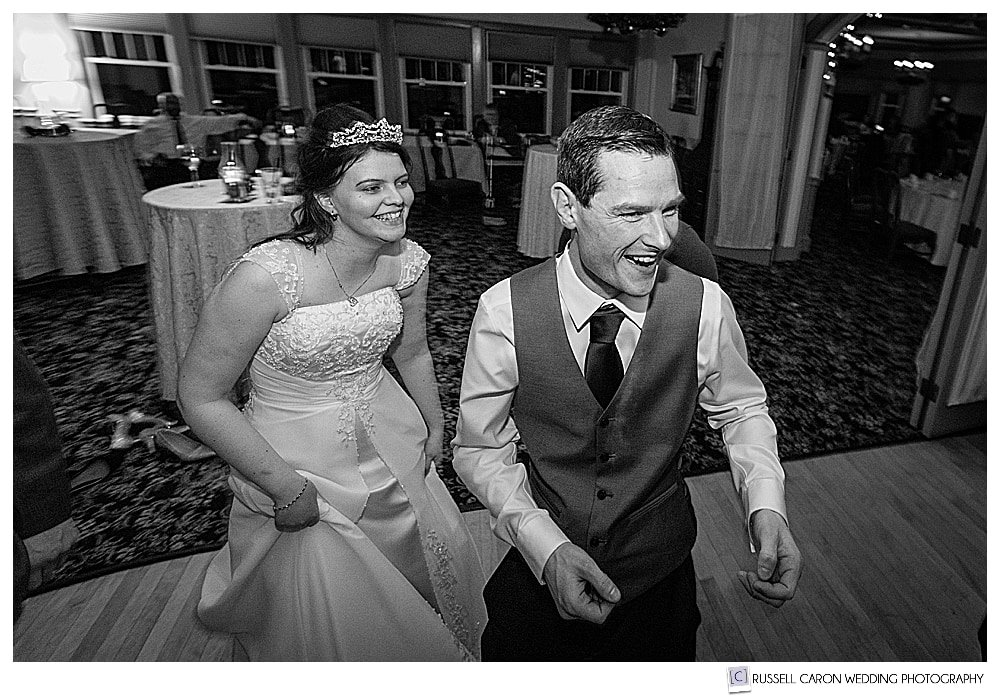 black and white photo of bride and groom laughing on the dance floor