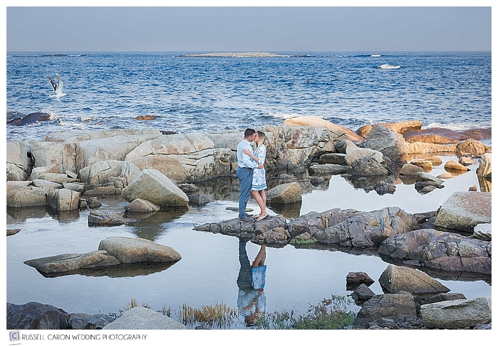 man and woman kissing on the rocks by the ocean