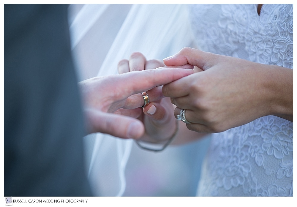 bride putting ring on groom's finger