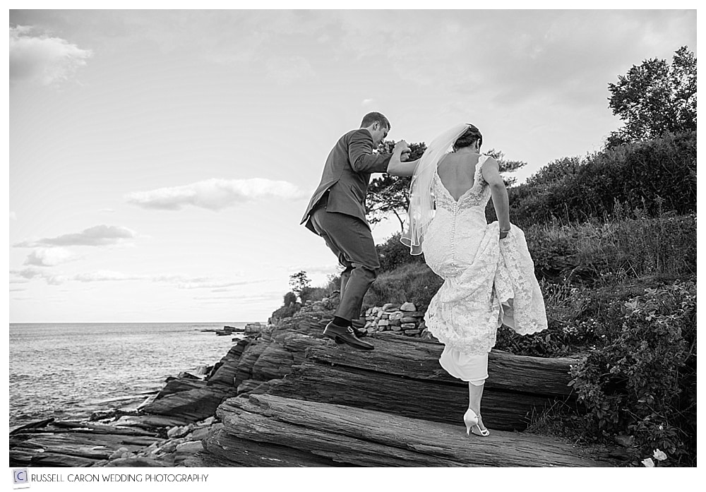 groom helping bride on the rocks