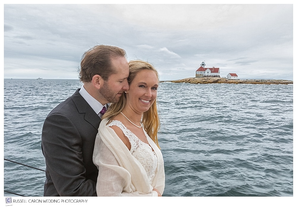 bride and groom sailing with lighthouse behind