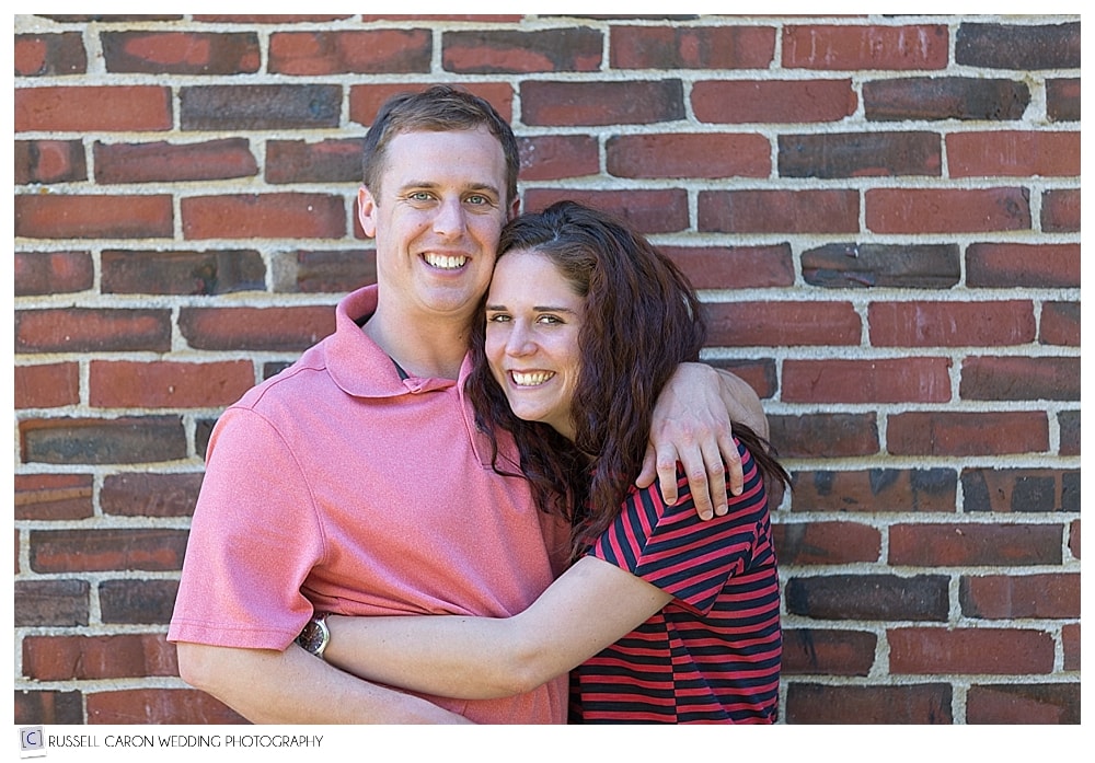 couple standing in front of brick wall