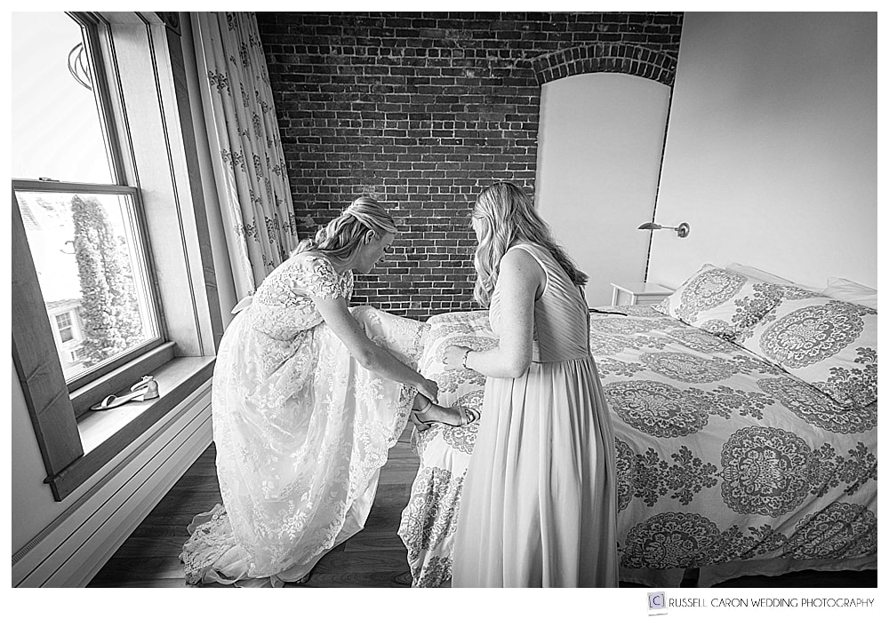 black and white photo of bride putting shoes on