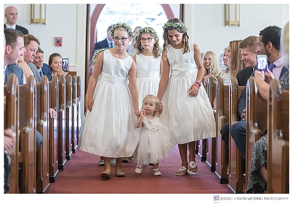 flower girls walk down the aisle at Our Lady of Good Hope Church in Camden, Maine