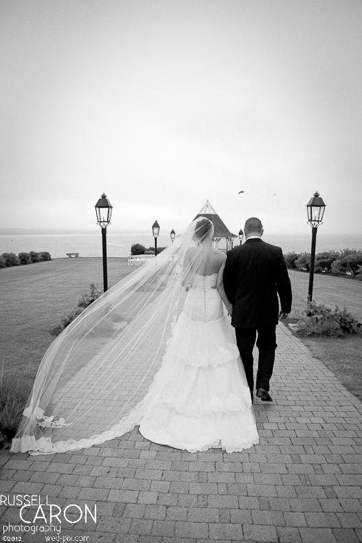 Bride and groom walking hand in hand with bride's veil blowing