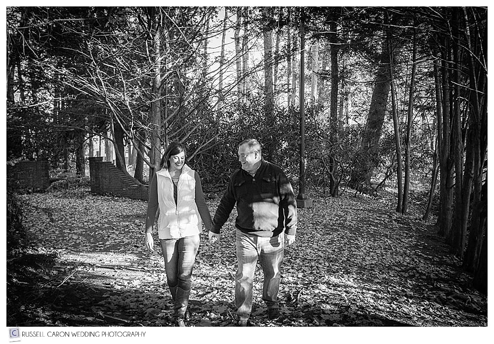 man and woman walking hand in hand in the woods