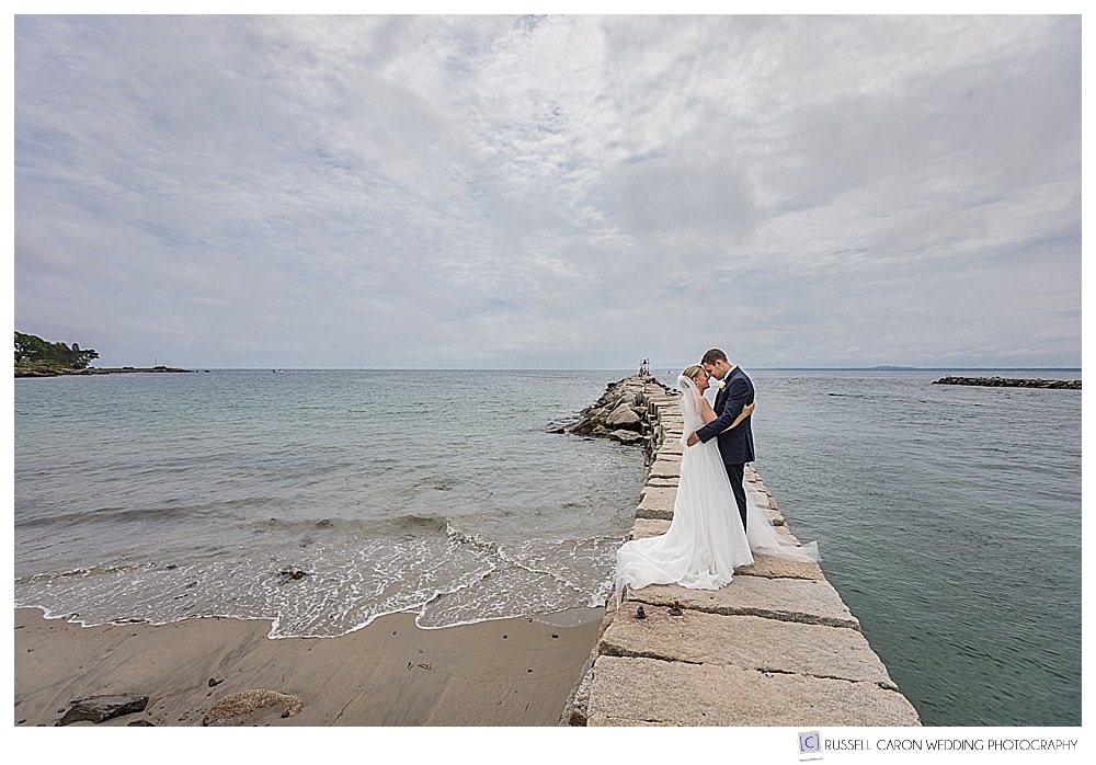 bride and groom kissing on the kennebunkport breakwater, kennebunkport, maine