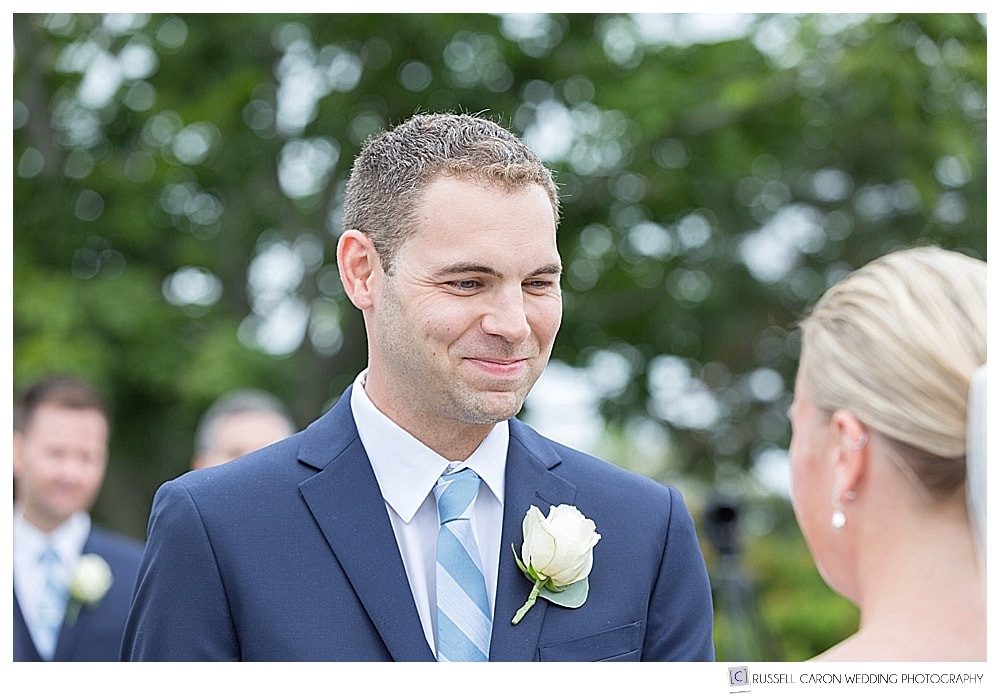 groom smiles at the bride during their wedding ceremony on the lawn at the Colony Hotel, Kennebunkport, Maine