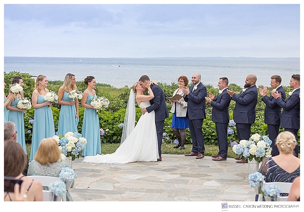 bride and groom's first kiss at their outdoor Colony Hotel wedding,