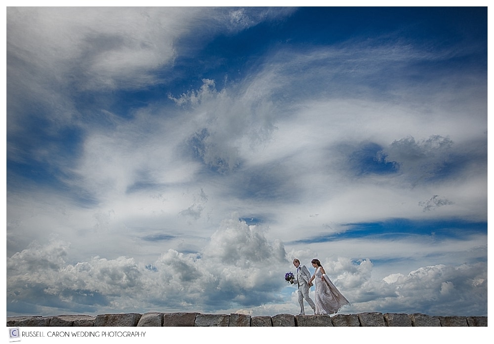bride and groom walking on kennebunkport maine breakwater