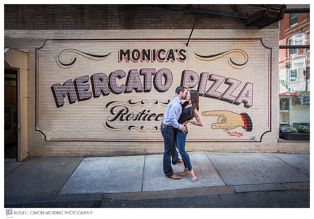man-and-woman-kissing-in-front-of-sign
