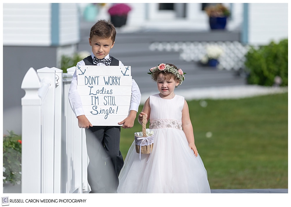 flower girl and ring bearer walking down the aisle at an outdoor wedding