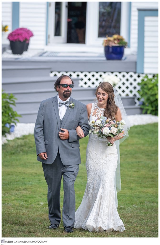 bride and her father walk towards the backyard ceremony site