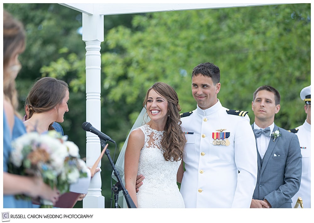 bride and groom standing side-by-side during their Dresden Maine wedding ceremony, while a bridesmaids reads