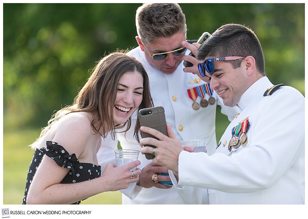 wedding guests laugh at a cell phone