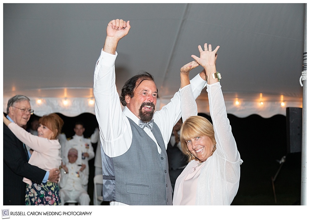 brides parents dancing, with their arms up in the air