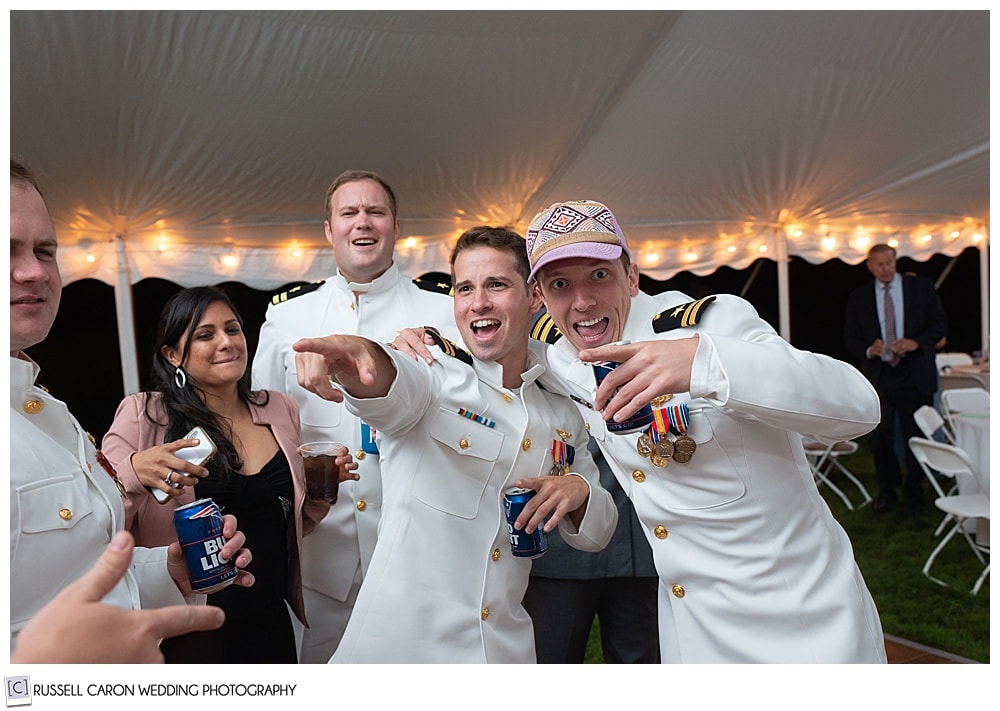 two men in dress whites having fun at a wedding reception