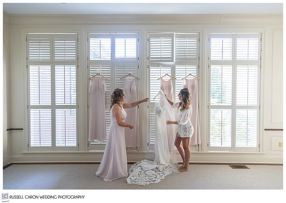 bride and matron of honor, getting the bride's dress of its hanger