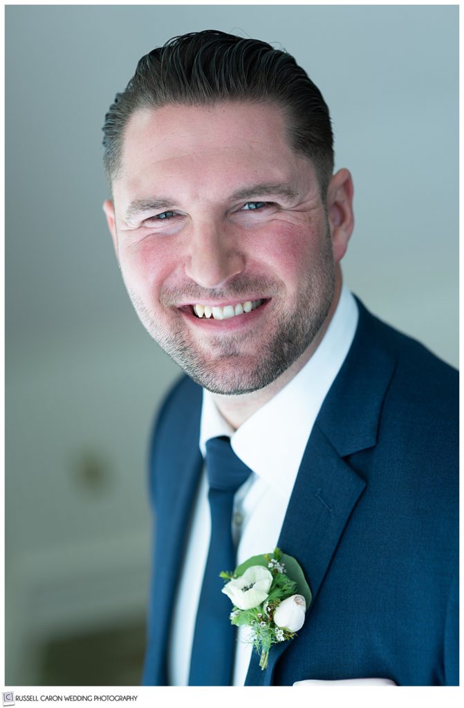 portrait of a smiling groom wearing a blue suit and tie