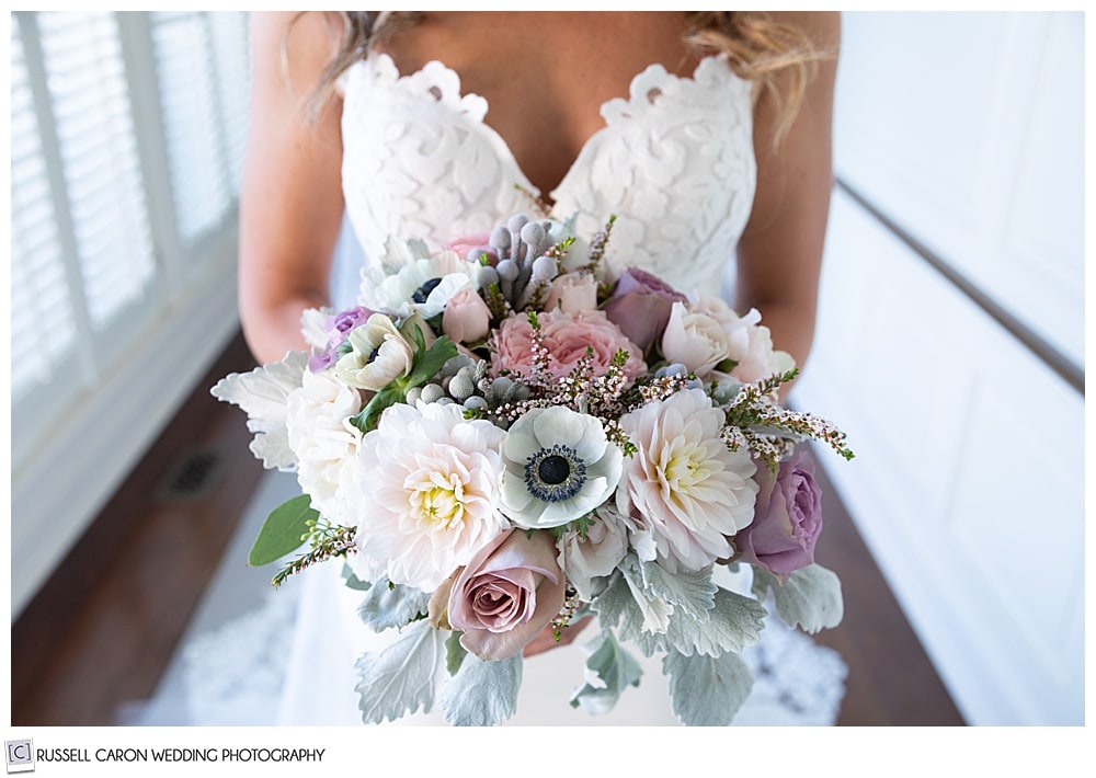 bride holding a beautiful bridal bouquet of pastel pink, yellow, lavender, and green bouquet from Seasons Downeast Designs