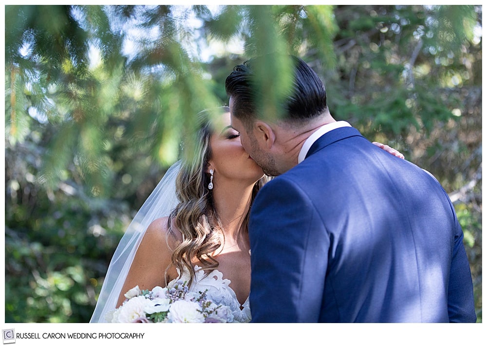 bride and groom kissing in a grove of trees during their first look photos